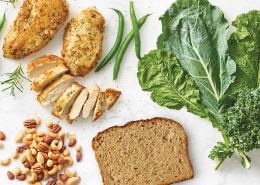 Slice of wheat bread, kale & greens, cooked chicken, and pile of nutes