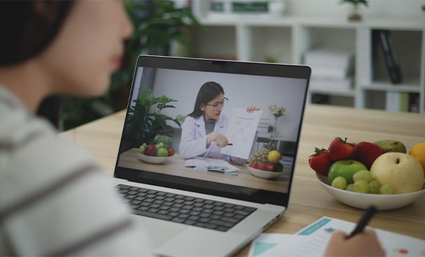Woman taking notes while in a telenutrition session with a dietitian