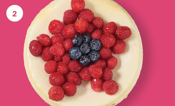fresh berries in a flower shape on top of a plain cheesecake