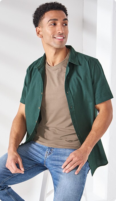 A man wearing a featured outfit with green over shirt and tan under shirt